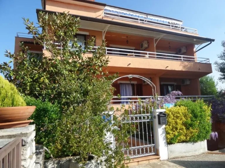 La maison Apartmani Lina depuis la rue : façade orange, balcons et entrée dans la verdure