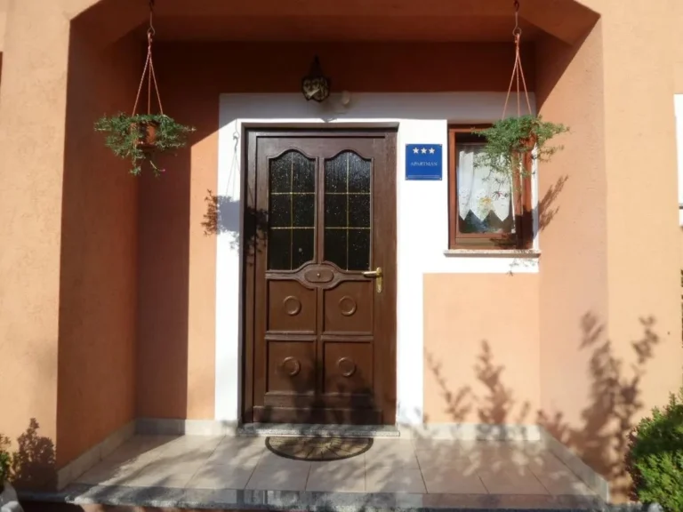Porte d'entrée en bois avec fleurs suspendues et plaque trois étoiles
